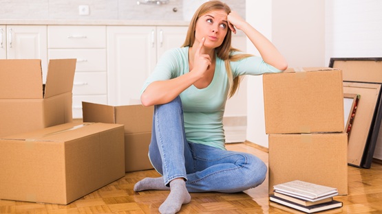 Kobieta pakuje rzeczy do przeprowadzki za granicę. Obok niej kilka kartonów gotowych do wysyłki przez Paczkomat.