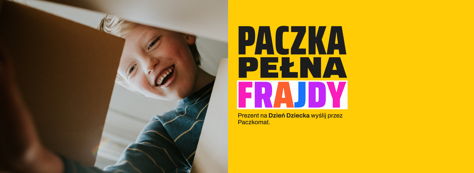 Uśmiechnięte dziecko zaglądające do paczki. Paczka pełna frajdy. Prezent na Dzień Dziecka wyślij przez Paczkomat.