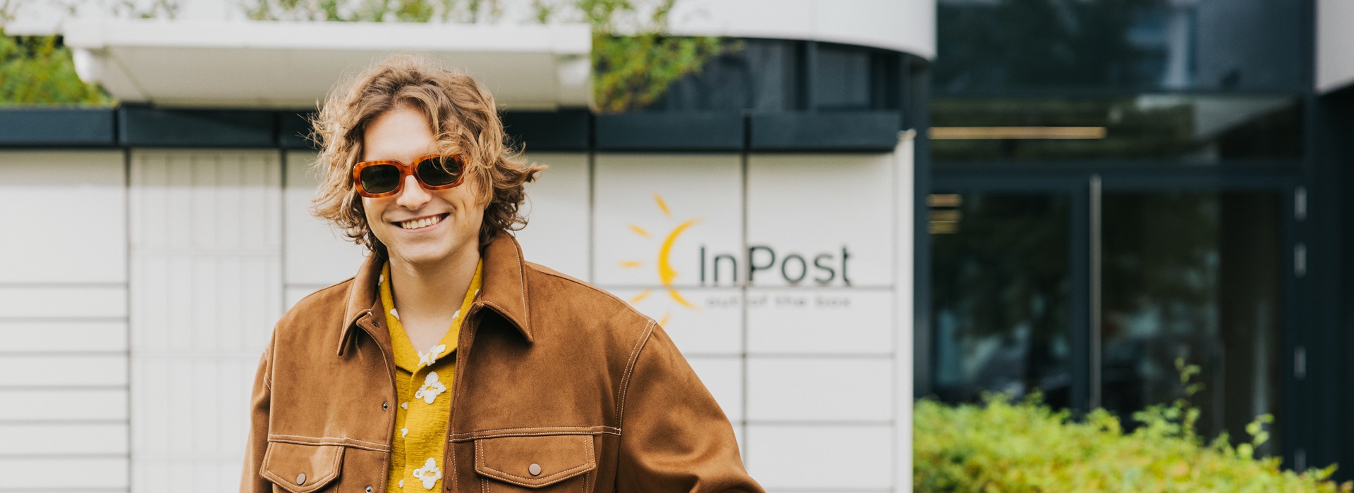 Uśmiechnięty chłopak przed maszyną Paczkomat