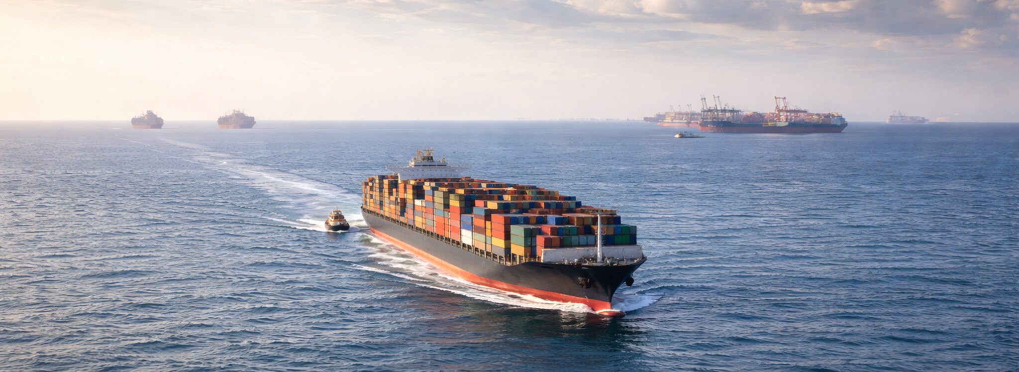 Transport morski frachtowy: z oddali widoczny statek kontenerowy płynący po otwartym morzu, z kolorowymi kontenerami na pokładzie.