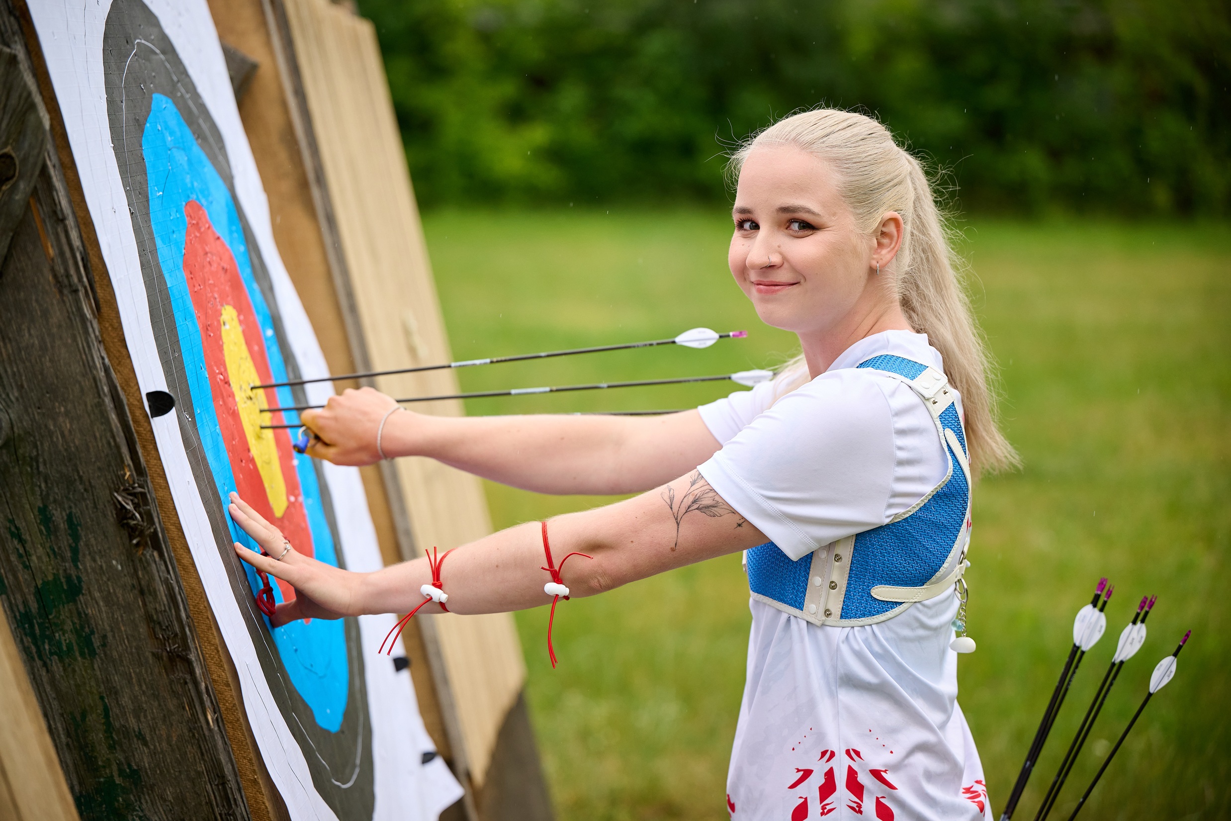 Karina Kozłowska uśmiecha się, wyciągając strzałę z tarczy strzeleckiej