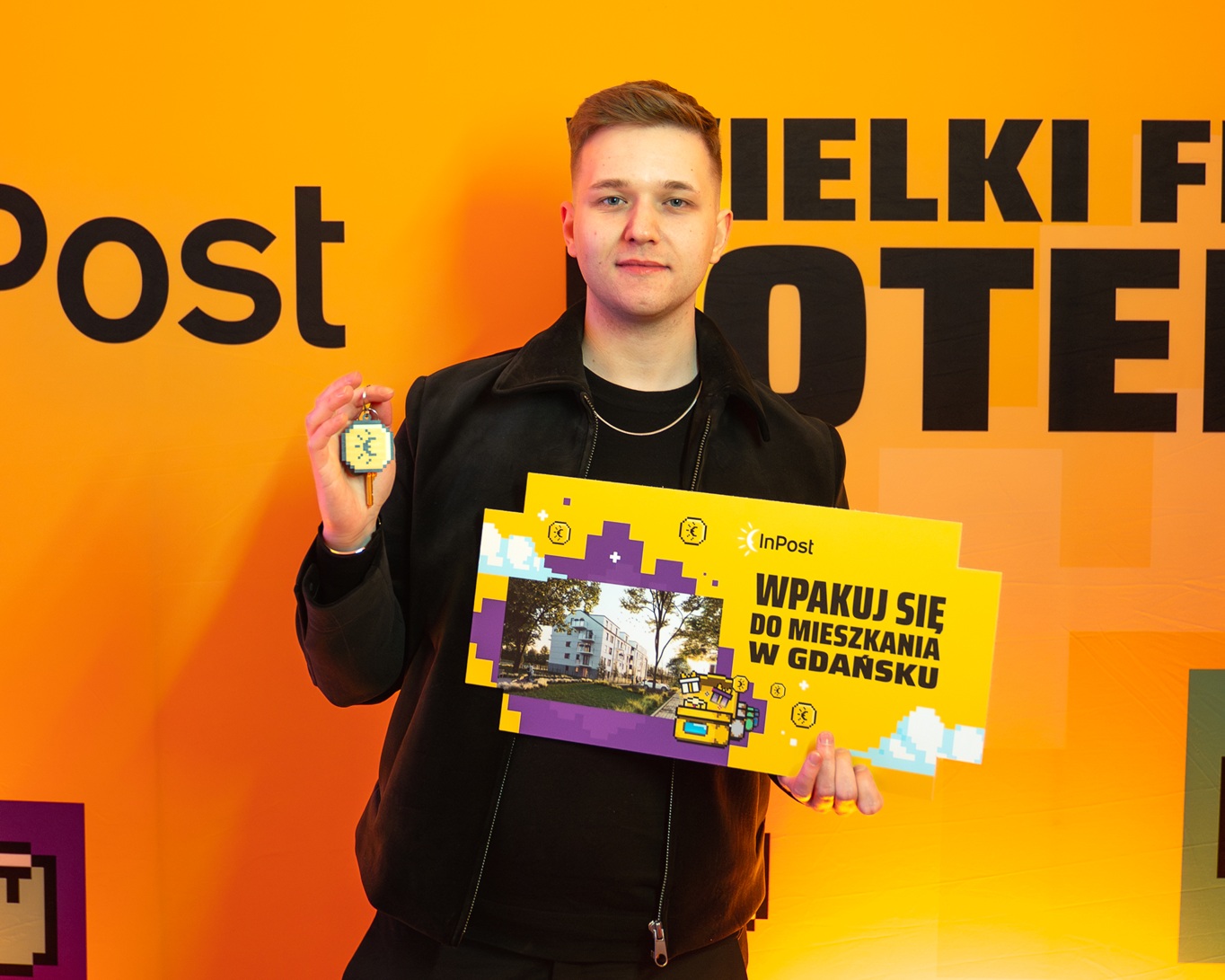 Zwycięzca nagrody w loterii InPost pokazuje klucze do mieszkania z brylokiem w kształcie InCoina