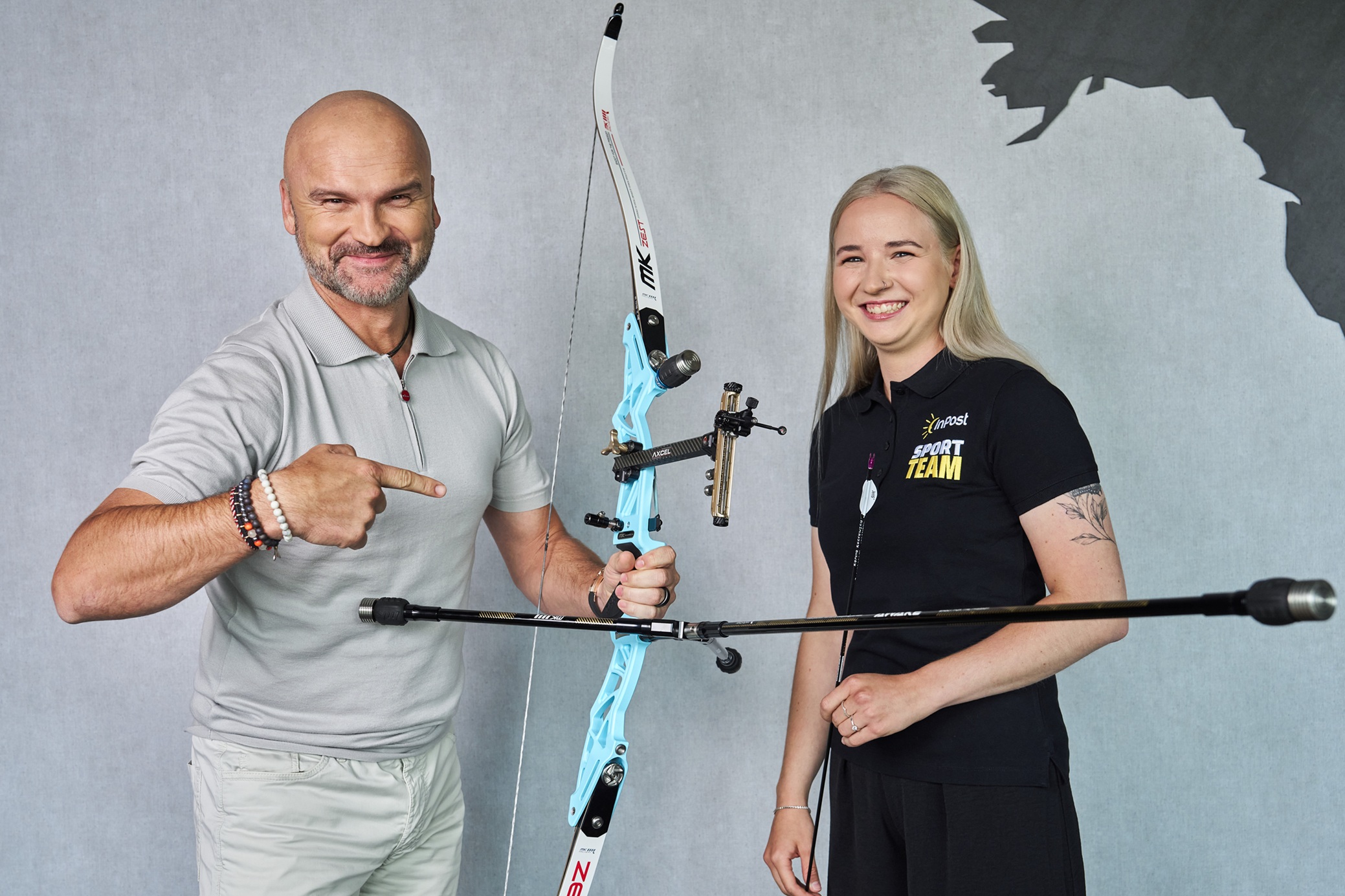 Rafał Brzoska i Karina Kozłowska uśmiechają się i pozują do zdjęcia z łukiem