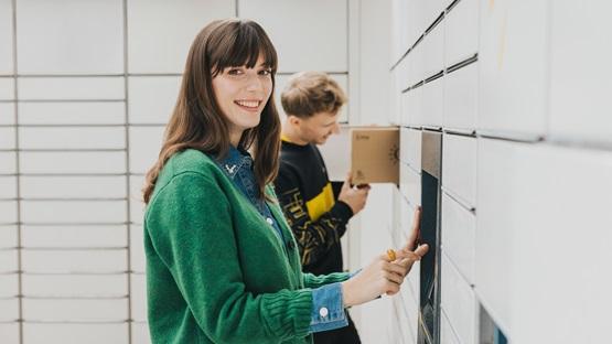 Uśmiechnięta kobieta przed maszyną Paczkomat.